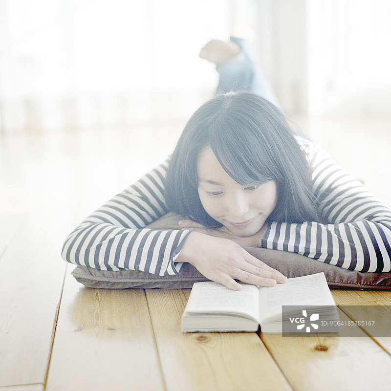 日本女人趴在地板上看书图片素材