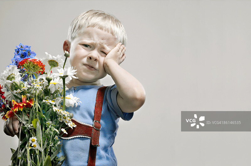 拿着一束鲜花嘟嘴的小男孩图片素材