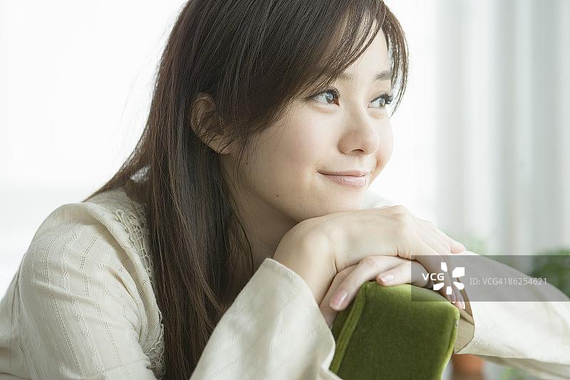 年轻女人在扶手椅上放松，看向远方图片素材