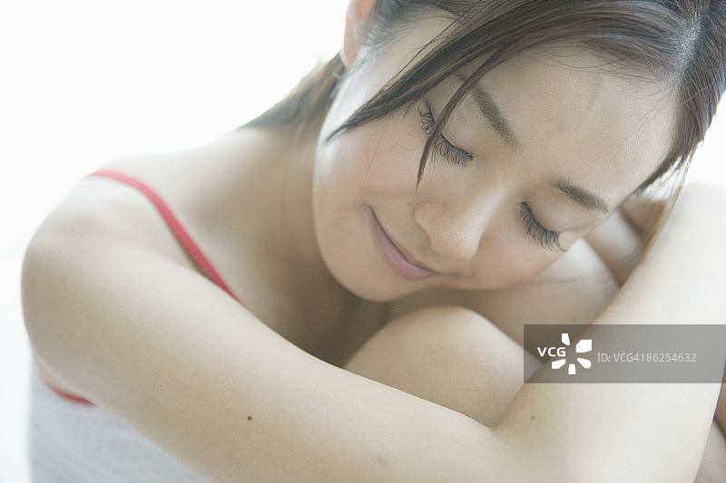 闭着眼睛的年轻女人抱着膝盖图片素材