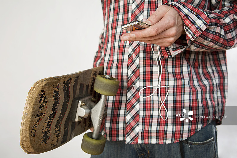 穿着格子衬衫使用MP3播放器的青少年男孩图片素材