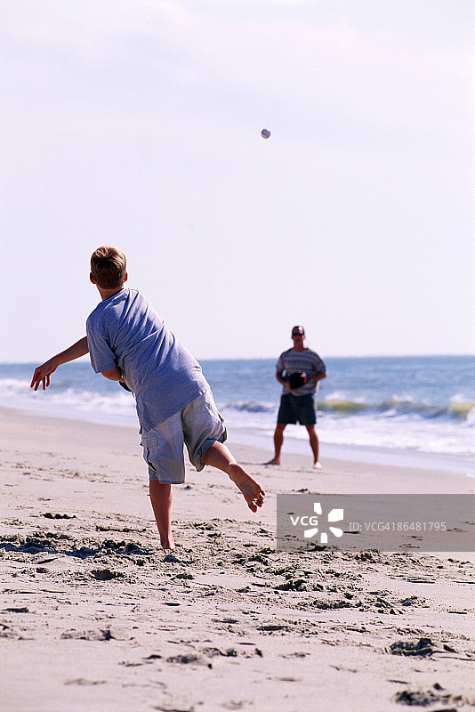 父子在沙滩上玩抛接游戏图片素材