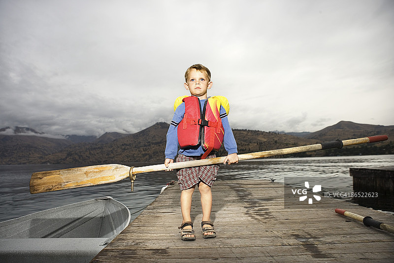 男孩在码头上拿着桨图片素材