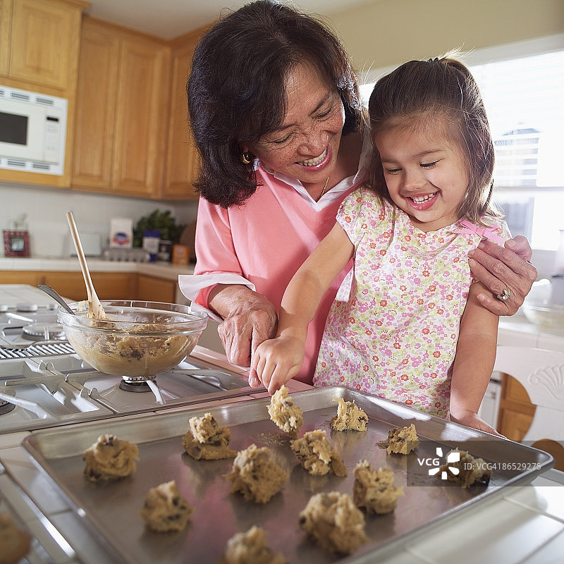 奶奶帮助孙女烤饼干图片素材