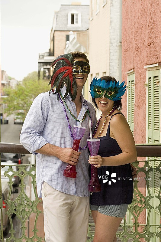 情侣戴着面具在阳台上喝酒图片素材