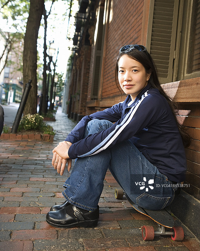 女子坐在滑板上图片素材