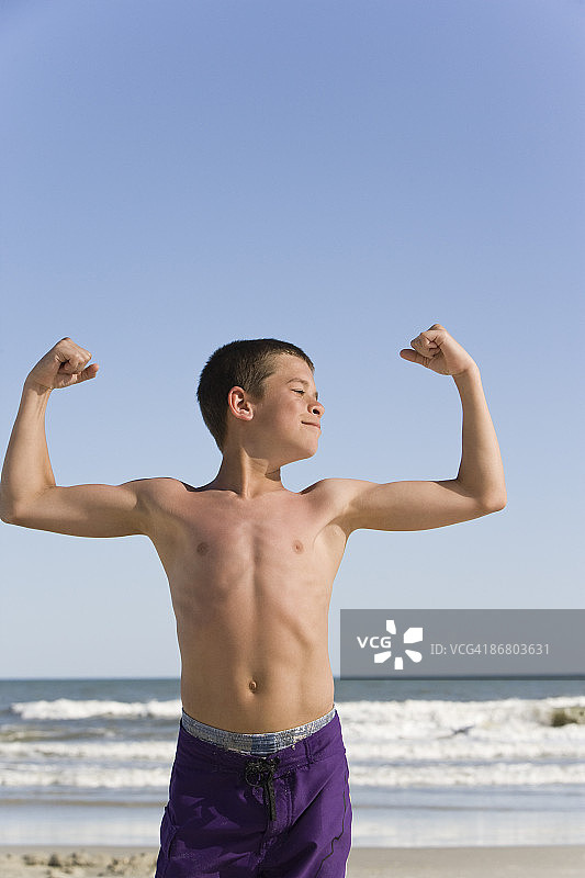 男孩在海滩展示手臂肌肉图片素材
