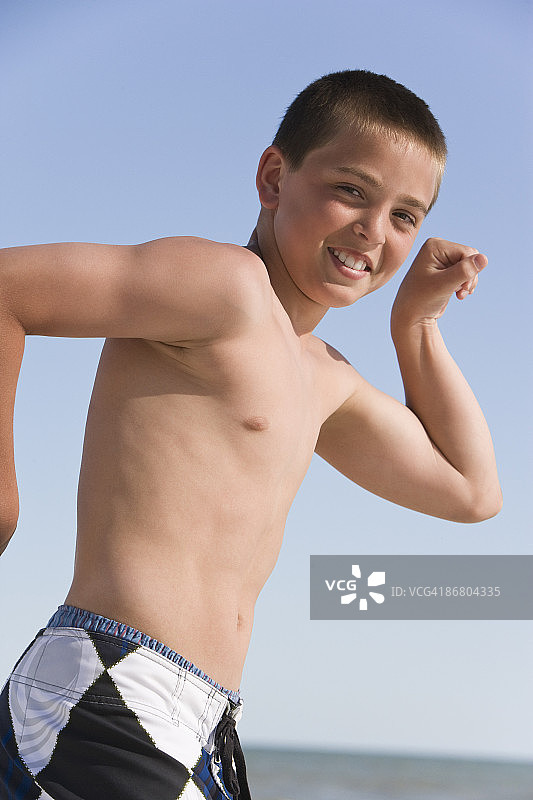 微笑的男孩展示手臂肌肉图片素材