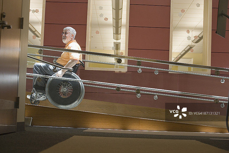 坐在轮椅上的中年男子在轮椅坡道上侧面像图片素材
