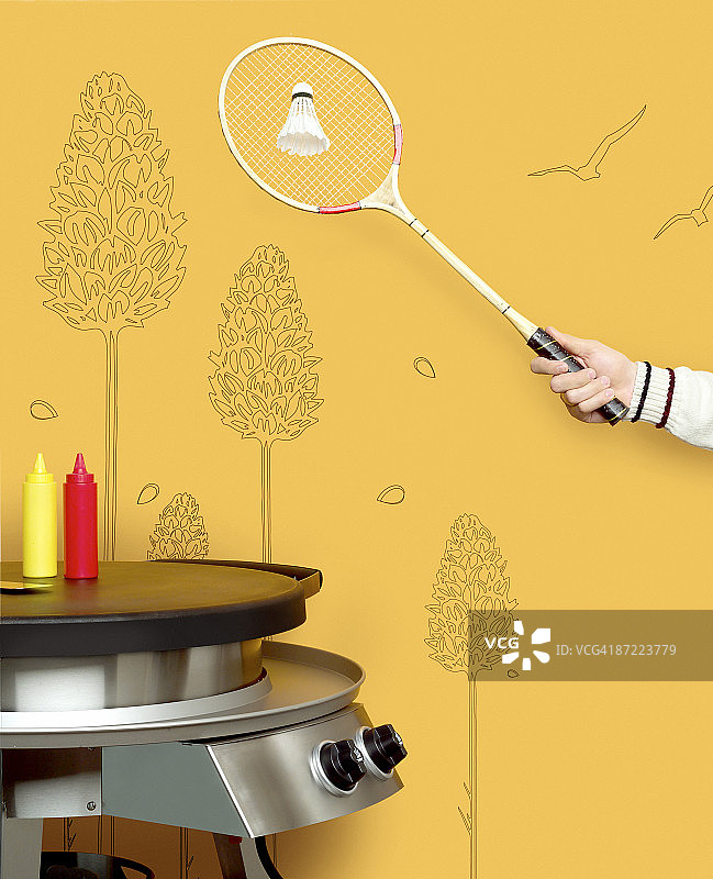 手持羽毛球拍，背景是烧烤图片素材