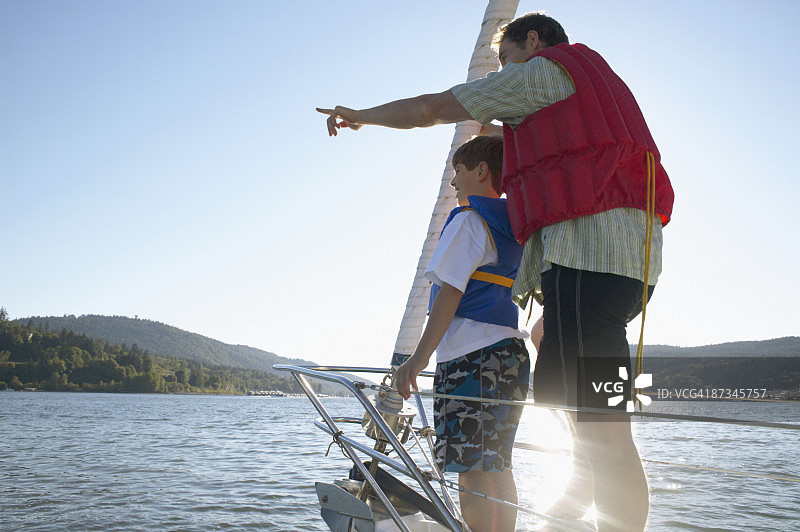 父子身穿救生衣站在船尾眺望大海图片素材