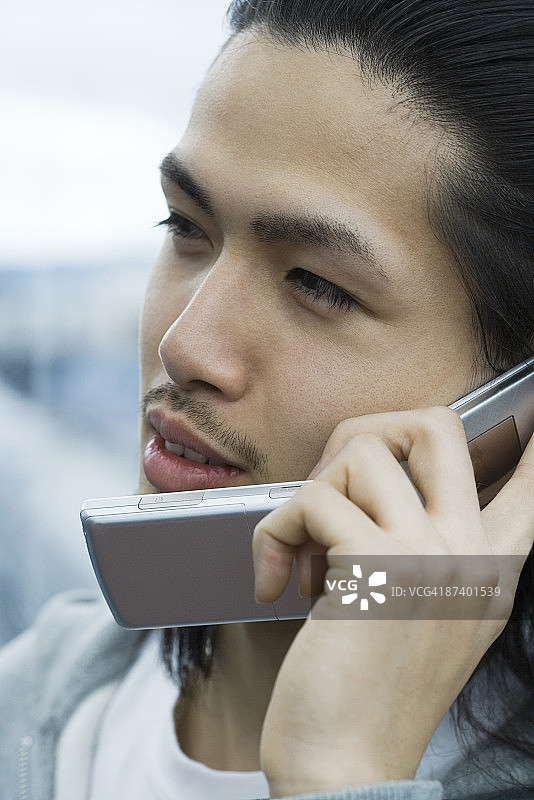 年轻男子在使用手机，看向别处图片素材