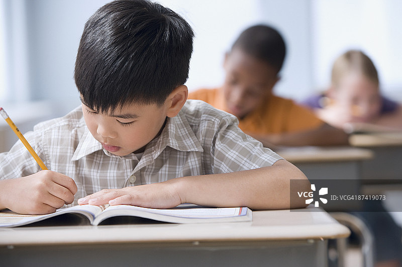 在教室里写作业的亚洲男孩图片素材