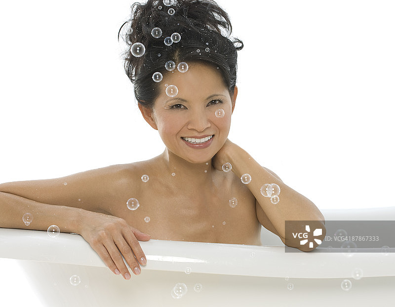 在满是泡泡的浴缸里的年轻亚裔女性图片素材