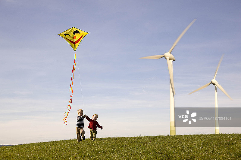 两个男孩在风力涡轮机旁放风筝图片素材