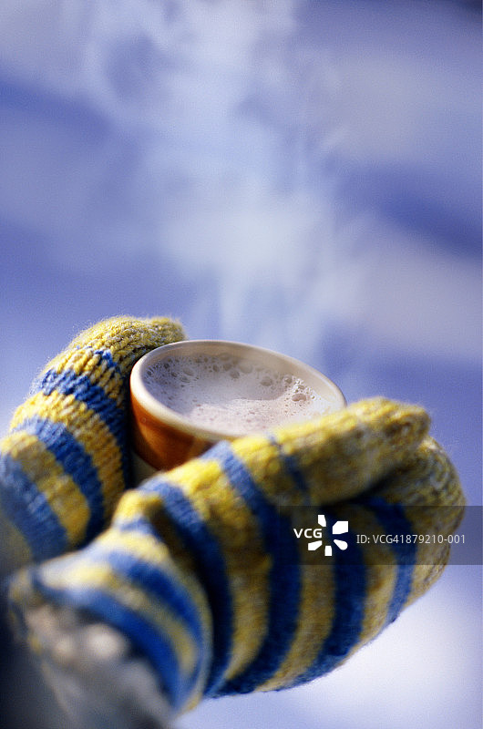 戴着手套的手捧着一杯可可的特写图片素材