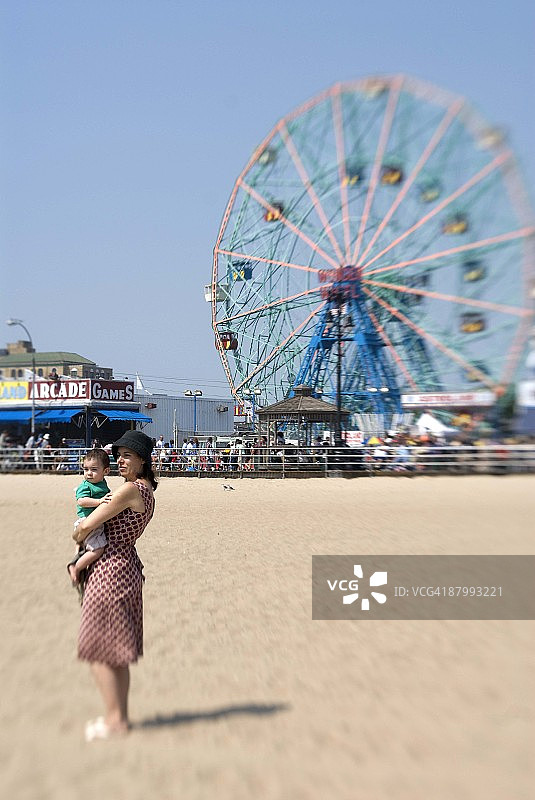 母子在海滩上，背景是嘉年华图片素材