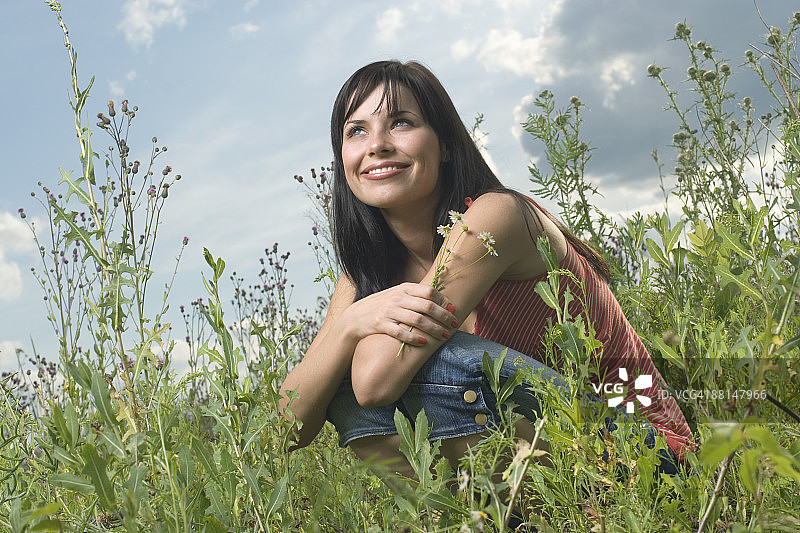 年轻女人坐在草地上手持鲜花的肖像图片素材