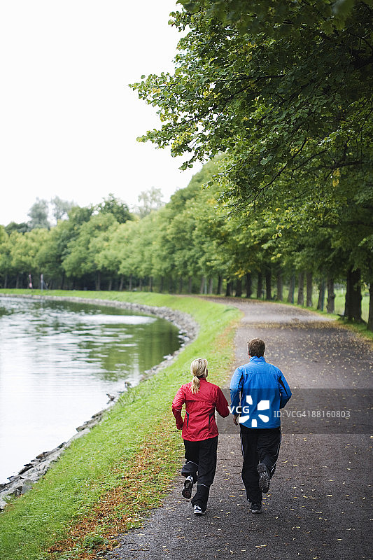 一对夫妇在瑞典的运河边慢跑图片素材