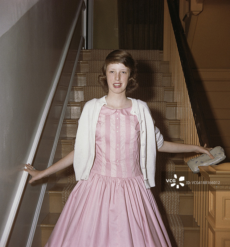 身穿粉色连衣裙站在楼梯上的复古少女图片素材