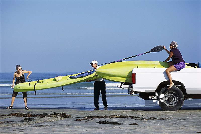 朋友们在海滩卸皮划艇图片素材