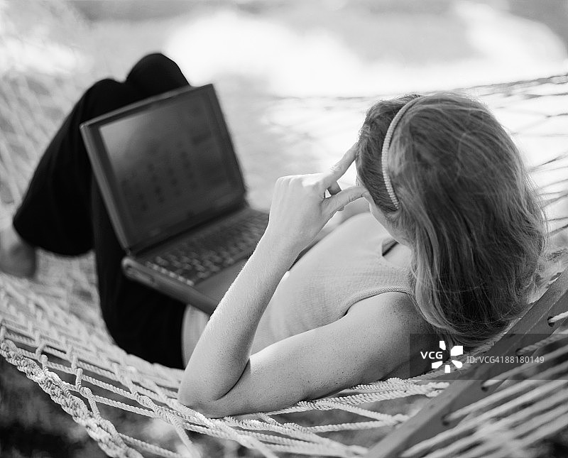 在吊床上使用笔记本电脑的女人图片素材