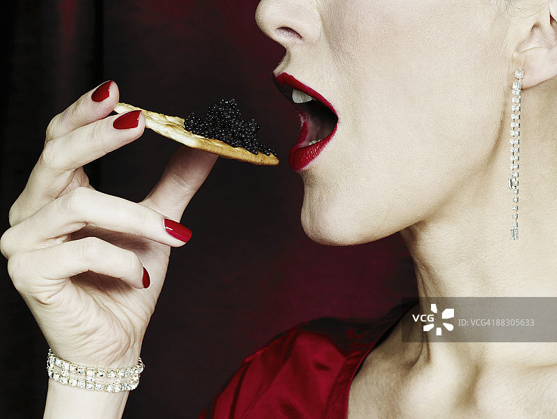 在饼干上吃鱼子酱的女人图片素材