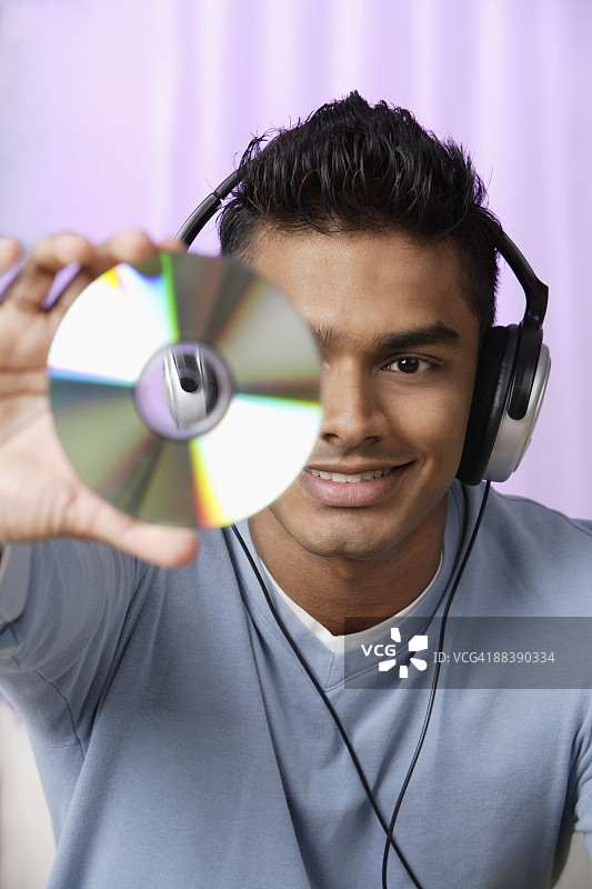 戴耳机的年轻男人手持光盘图片素材