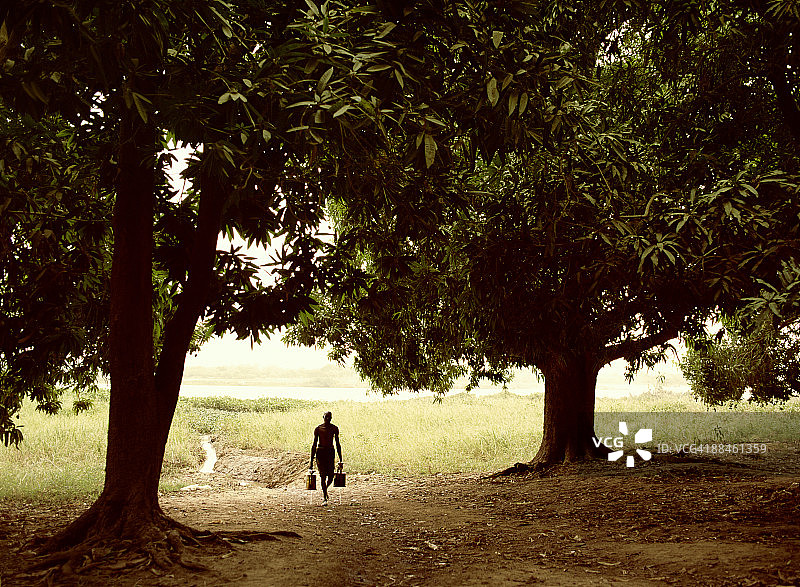 在尼日尔河边用喷壶浇水的男人图片素材