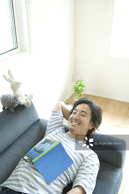 躺在沙发上微笑的年轻男人图片素材