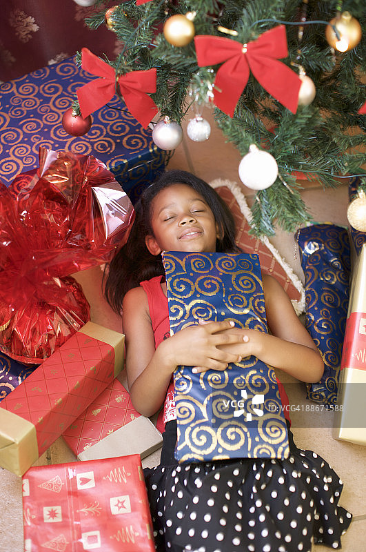 女孩躺在圣诞树前的礼物堆中，南非夸祖鲁-纳塔尔省彼得马里茨堡图片素材