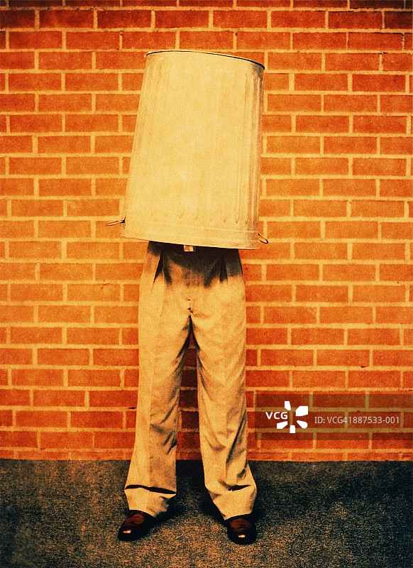 站在墙前，头顶纸篓的男人图片素材