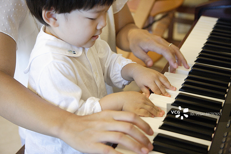 男孩和他的母亲一起弹钢琴的侧面轮廓图片素材