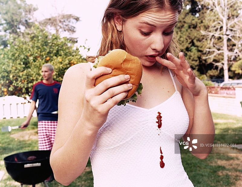 少女看着白色连衣裙上的番茄酱渍图片素材