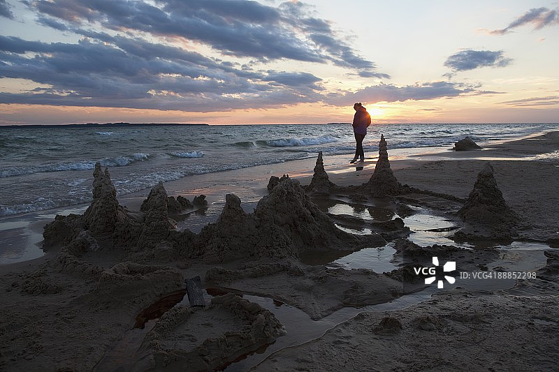 美国密歇根州比弗岛日落时独自在海滩上行走的人图片素材