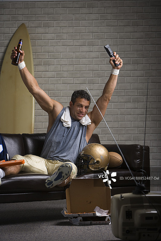 足球运动员在沙发上观看足球比赛并欢呼图片素材