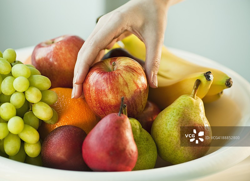 女人手从果盘里拿苹果图片素材