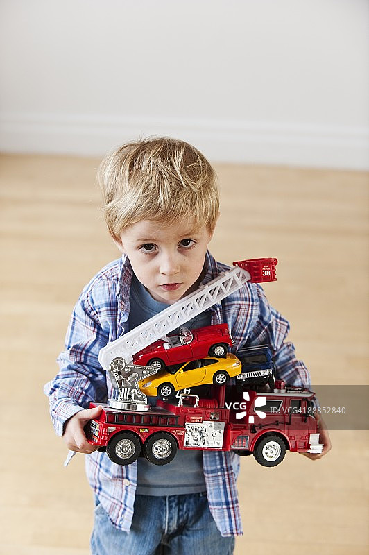 男孩（4-5岁）手持玩具消防车和汽车的肖像图片素材