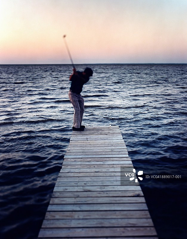 男人在美国阿拉巴马州牡蛎湾国家野生动物保护区的码头边缘发球图片素材