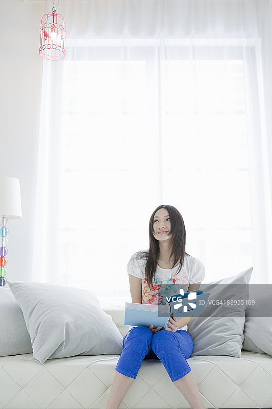 年轻女人在沙发上抬头看图片素材