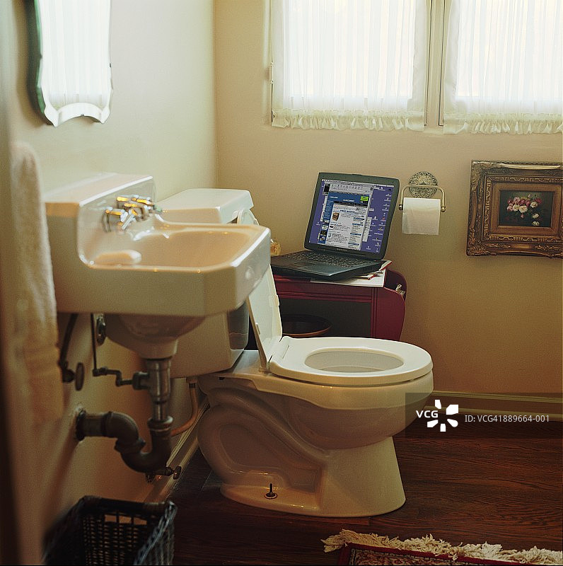 浴室：马桶旁的笔记本电脑图片素材