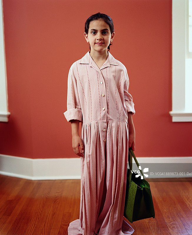 穿着女士连衣裙，拿着手提包的小女孩（8-10岁）肖像图片素材