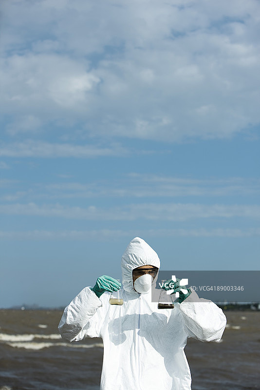 穿着防护服的人员拿着装满污染水的烧瓶图片素材