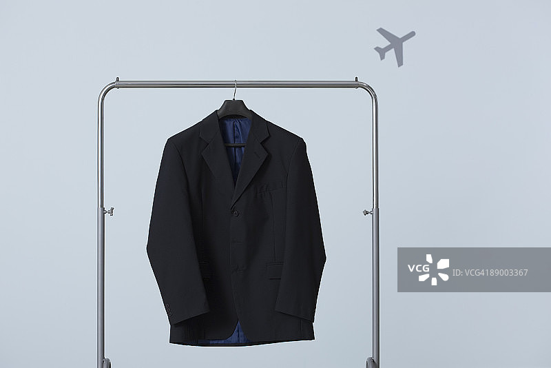 挂在衣架上的男士西装外套，背景是飞机图片素材