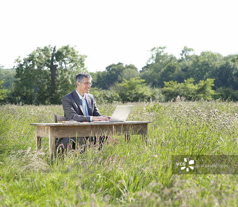 商务男士坐在乡村的办公桌旁图片素材