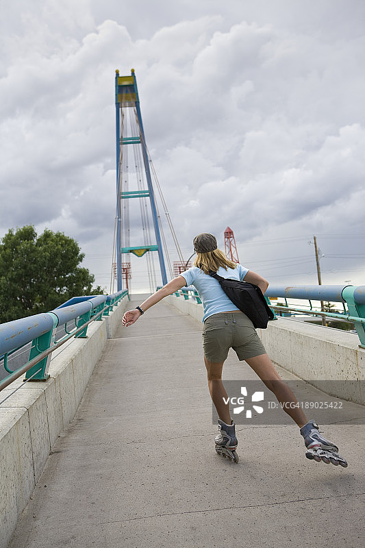 女人在人行天桥上玩轮滑图片素材
