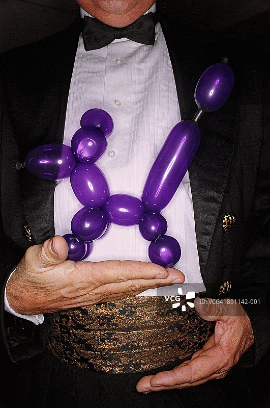 魔术师单手拿着紫色气球动物特写图片素材