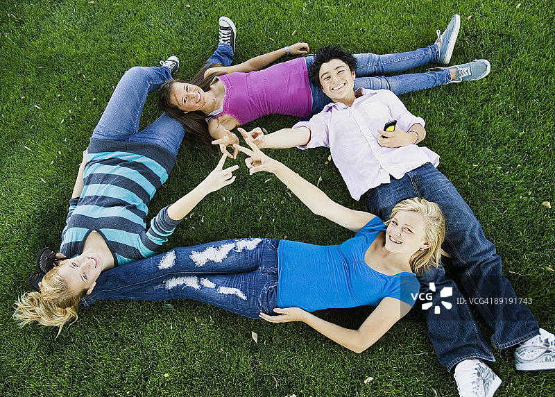 青少年躺在草地上做出和平手势图片素材