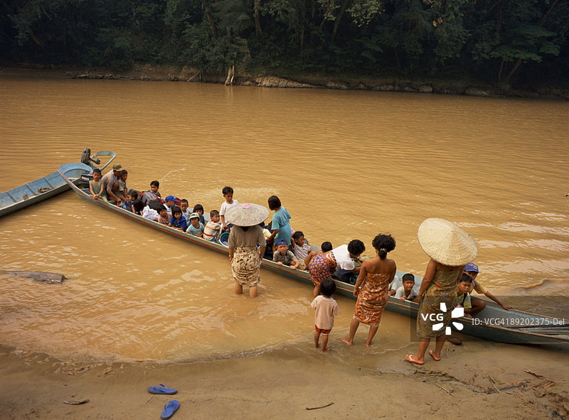 马来西亚沙捞越，卡提巴斯河：满载着上学儿童的长舟，母亲们送别图片素材