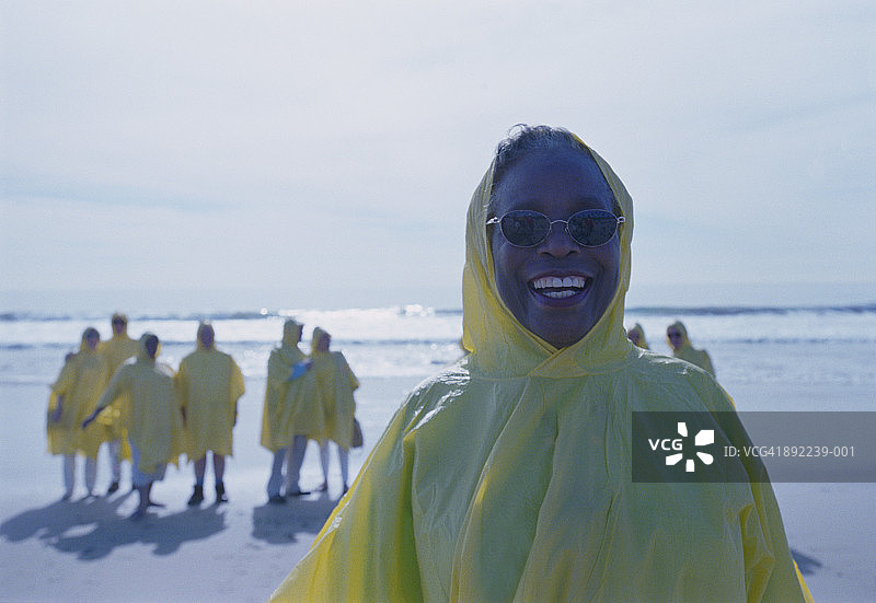 一群老年人在海滩上穿着雨衣，前景是一位女士图片素材
